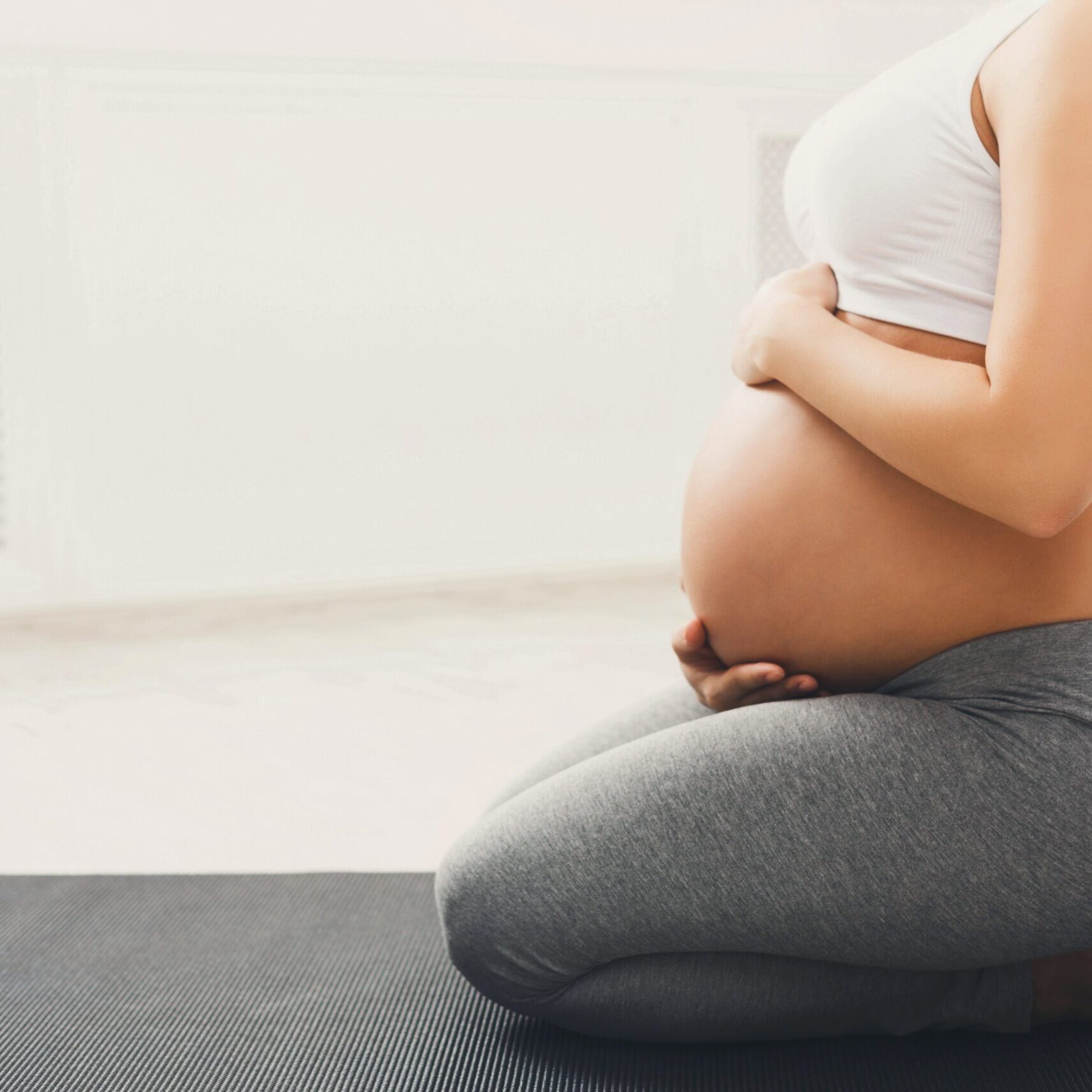 Unrecognizable,Pregnant,Woman,Training,Yoga,In,Hero,Pose,,Caressing,Her